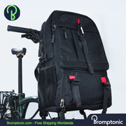 A large black Brompton-compatible trekking backpack with red accents, featuring multiple compartments and shoulder straps, displayed on a bicycle.